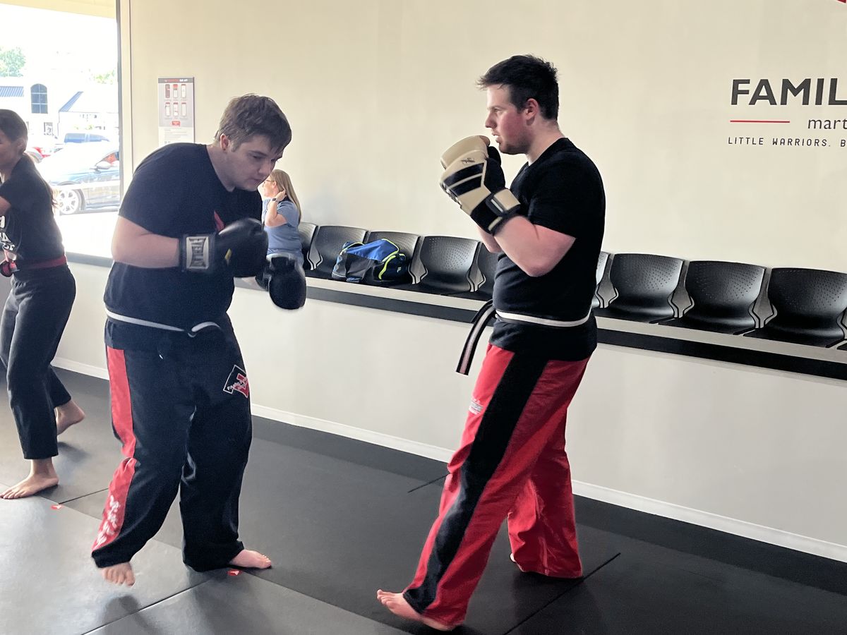 Two Gladiators students boxing in front of the Family First sign in Spring Hill